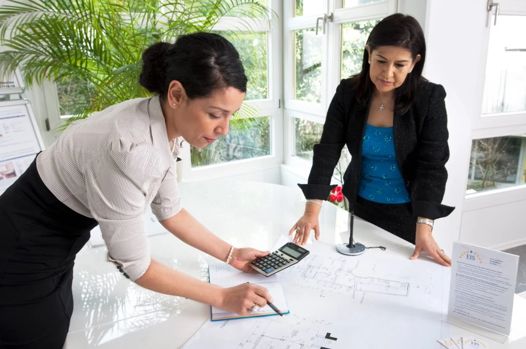 Two EIS Immobilien consultants reviewing building floor plans in a bright office.